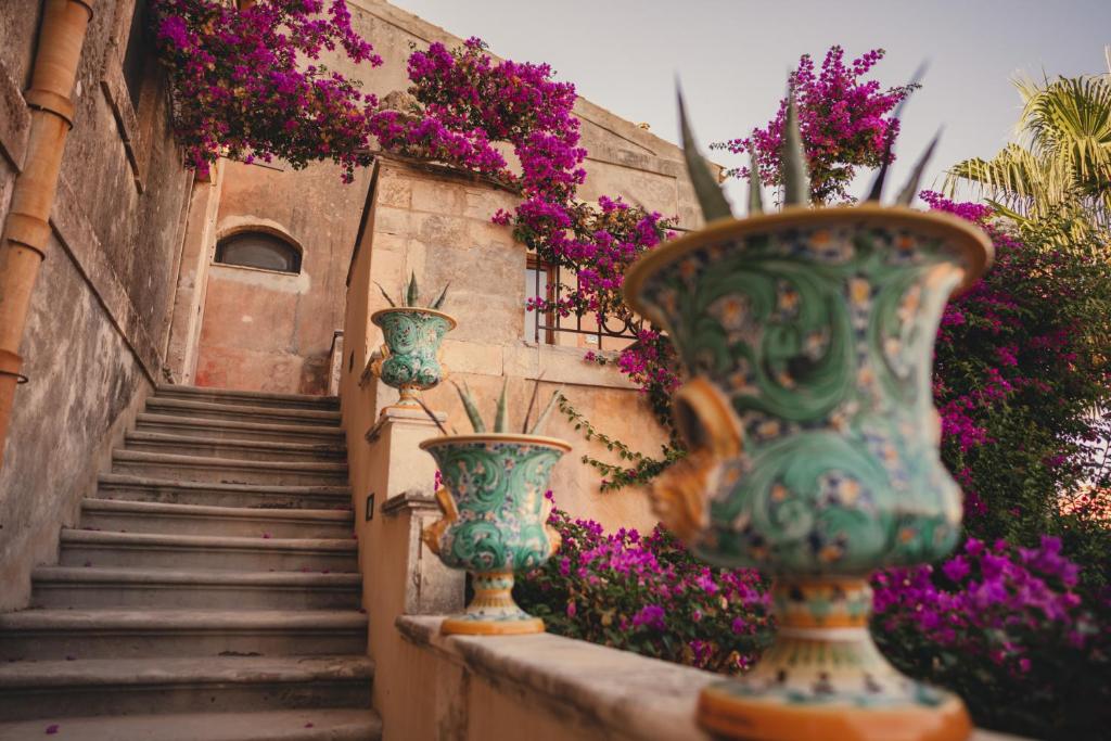 a group of vases sitting on a wall with flowers at Hotel Villa Giulia in Marzamemi
