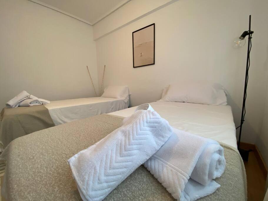 two beds in a room with white towels on them at Casa Mawi in Sopelana