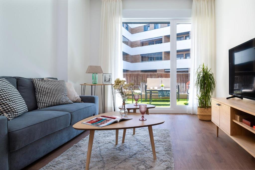 uma sala de estar com um sofá azul e uma mesa de centro em Misterhost La Florida Piscina y Terraza em Sevilha