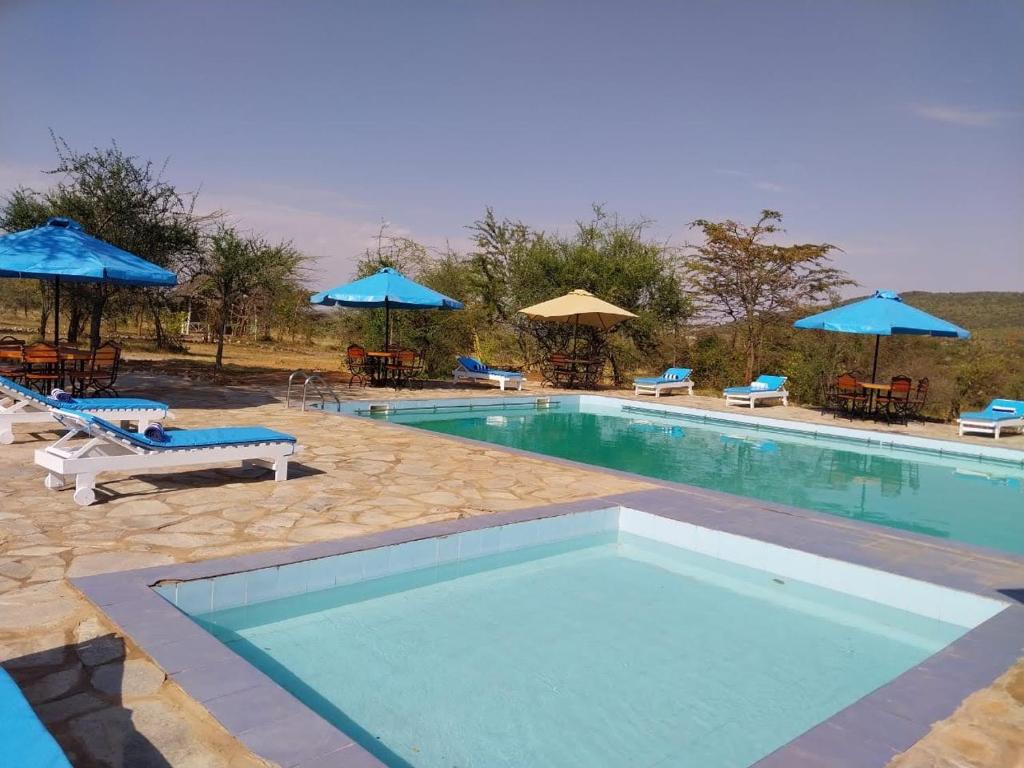 une grande piscine avec des chaises et des parasols dans l'établissement ELANGATA OLERAI LUXURY TENTED CAMP, à Narok