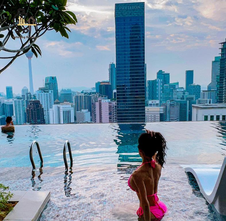 mała dziewczynka siedząca w basenie bez krawędzi z panoramą miasta w obiekcie 1 min to Pavilion KL Heart of Bukit Bintang by GBS w Kuala Lumpur