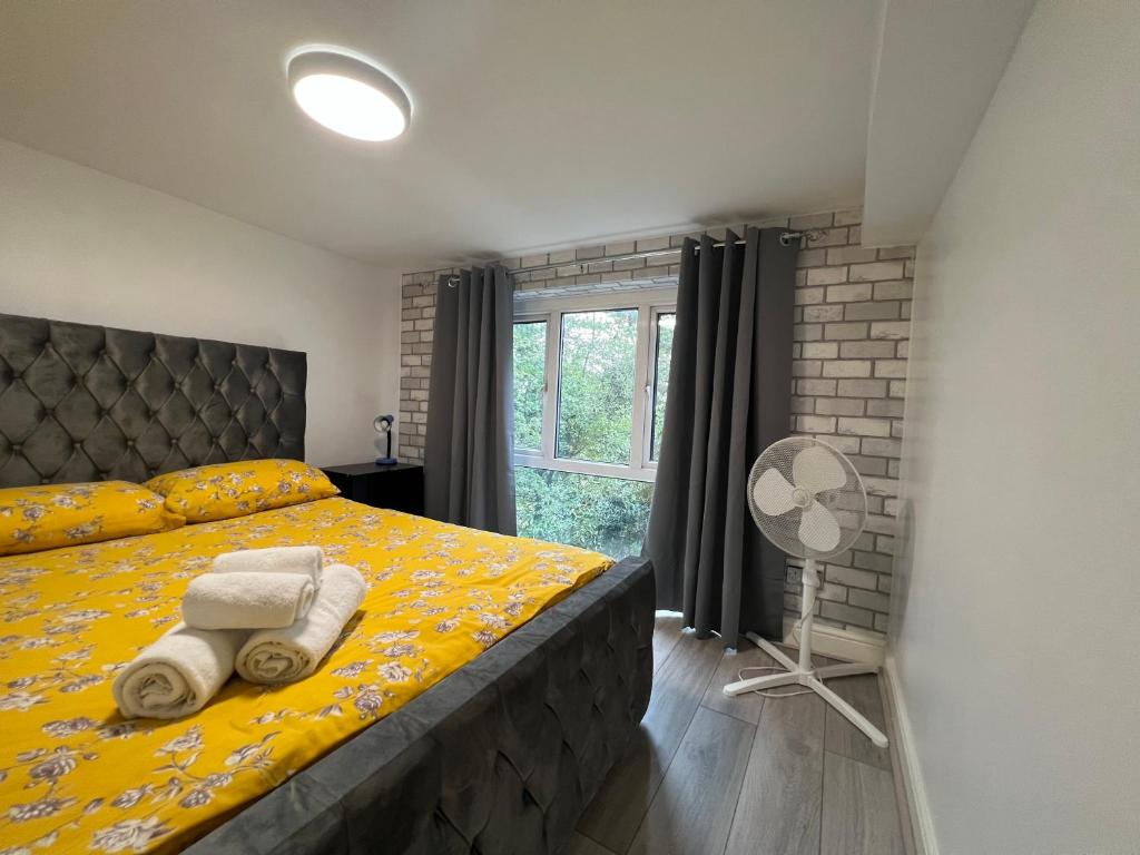 a bedroom with a yellow bed and a window at Comfy Apartments - Finchley Road in London