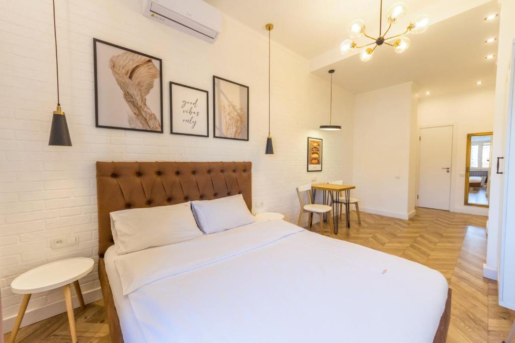 1 dormitorio con 1 cama blanca, mesa y sillas en Self Check-in Apartments en Kiev