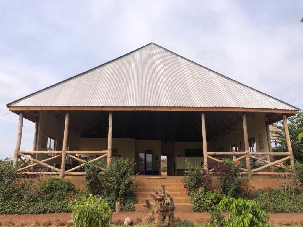 a building with a roof with stairs and flowers at Jua Manyara Lodge & Camp Site in Mto wa Mbu