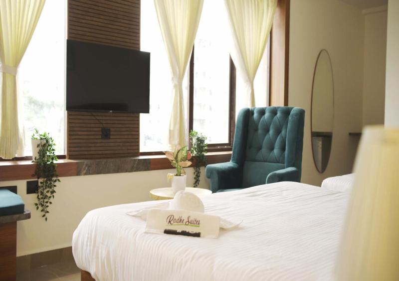een hotelkamer met een bed en een blauwe stoel bij Radhe Suites in Hyderabad
