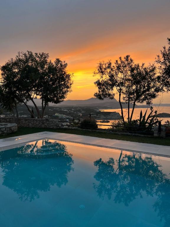 a swimming pool with a sunset in the background at SHIGAYA Boutique Villa in Plaka