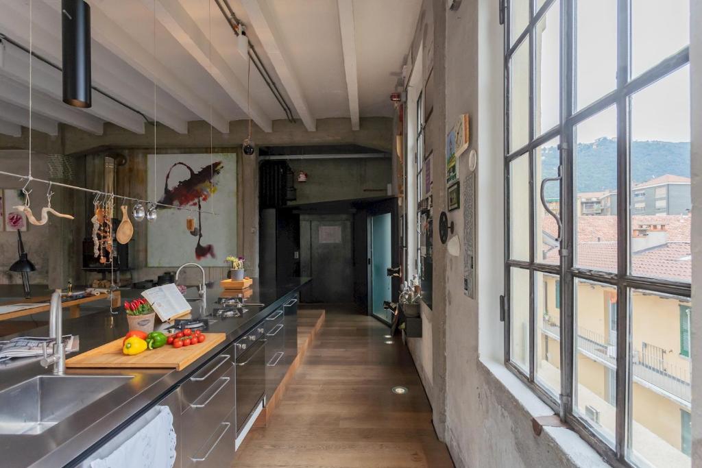 a large kitchen with a counter and a window at Design Loft with Private Parking by Rent All Como in Como