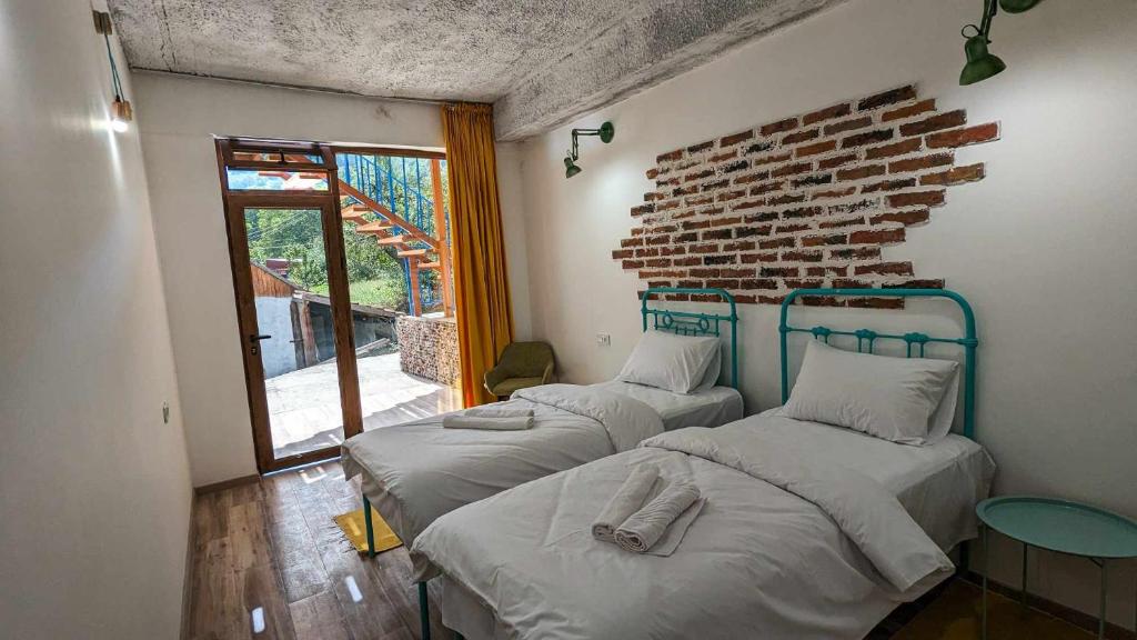 3 camas en una habitación con una pared de ladrillo en Hotel Arevi Gosh, en Gosh