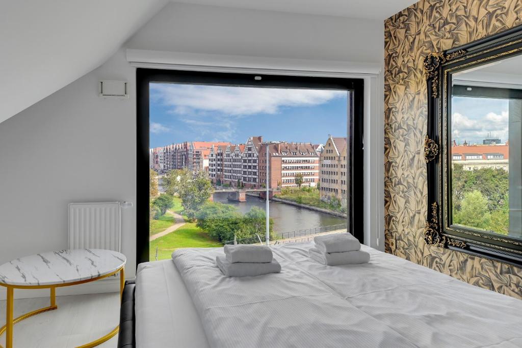 - une chambre avec une grande fenêtre, un lit et une table dans l'établissement Comfort Apartments Rezydencja Wintera, à Gdańsk