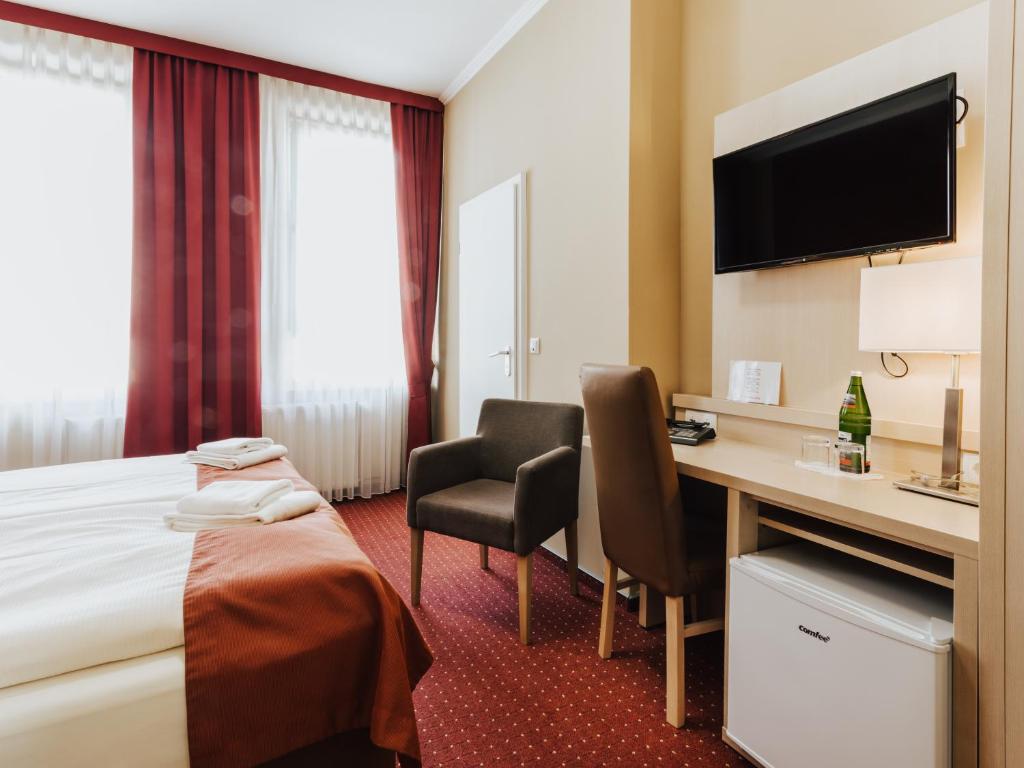 a hotel room with a bed and a desk and a tv at Hotel & Restaurant Wiggers in Bad Oldesloe