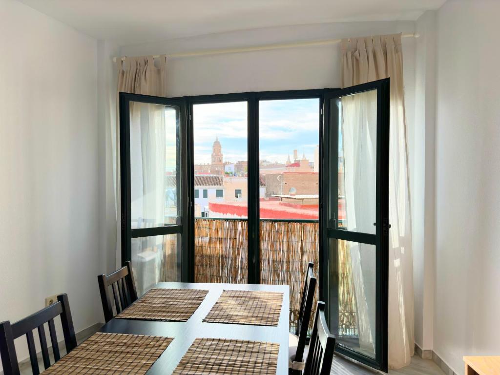 een eetkamer met een tafel en een groot raam bij Exclusive Malaga Apartments with Cathedral Views and Auto Check-in in Málaga