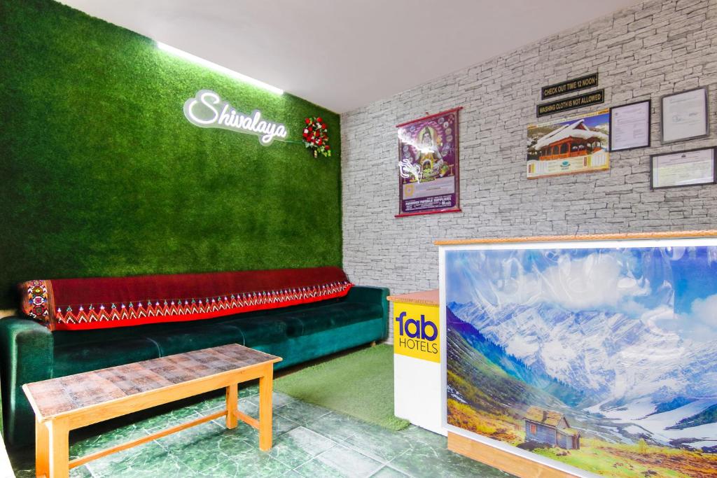 uma sala de estar com um sofá verde e uma mesa em FabHotel Negis Shivalay em Manali