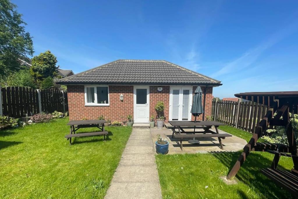 una casa con dos mesas de picnic en el patio en The Cubley Retreat en Sheffield