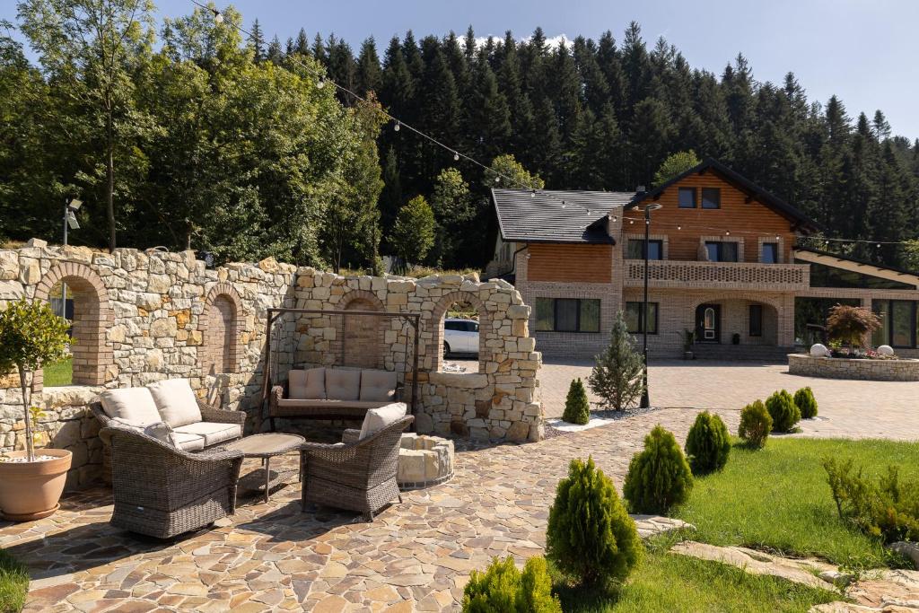 una casa y un patio con sillas y una pared de piedra. en Regatul Bucovinei, en Suceava