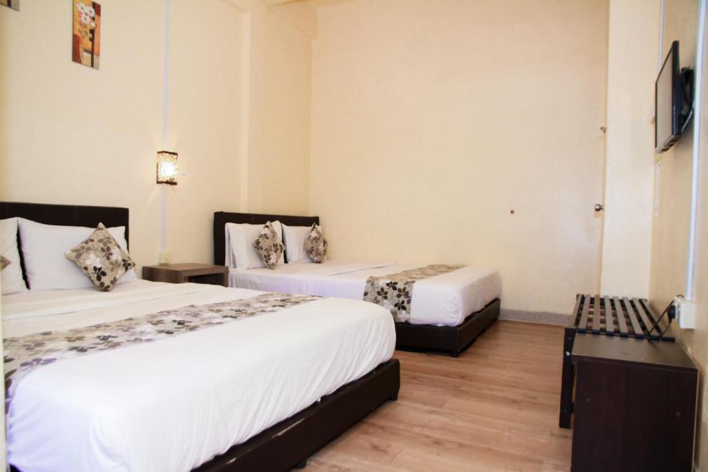 a hotel room with two beds and a television at Myra Hotel Mersing in Mersing