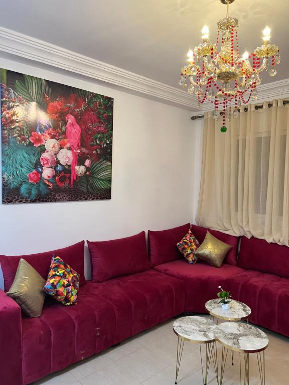 uma sala de estar com um sofá vermelho e um lustre em Flowers home em Oujda