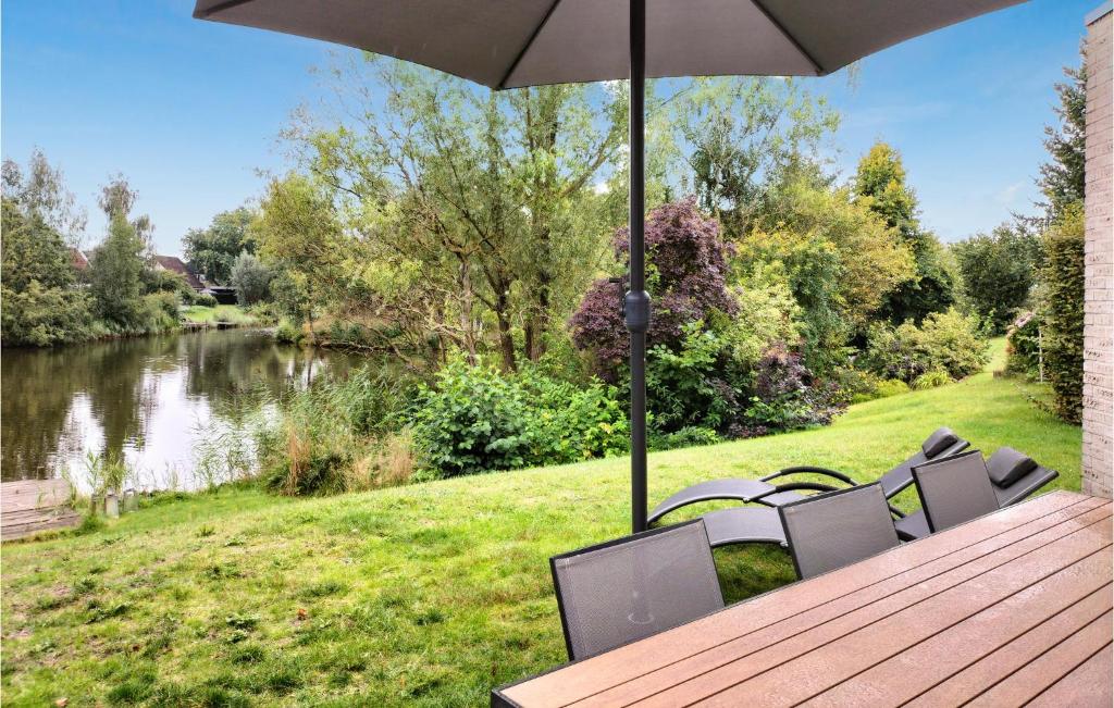 een houten tafel met stoelen en een parasol naast een rivier bij Lovely Home In Vlagtwedde With Kitchen in Vlagtwedde