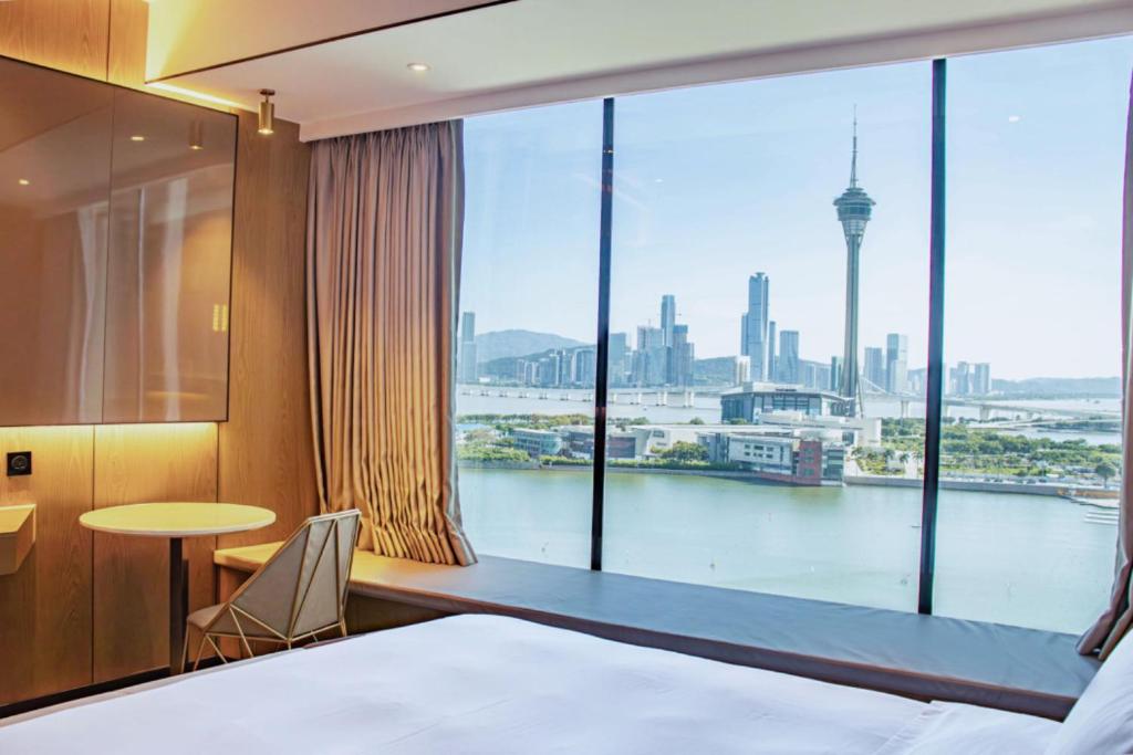 a bedroom with a large window with a view of the city at YOHO Treasure Island Hotel in Macau