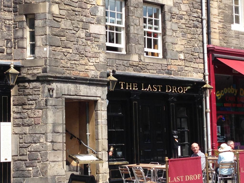 a man standing in front of a last drop restaurant at Grassmarket Old Town Boutique Apartment in Edinburgh