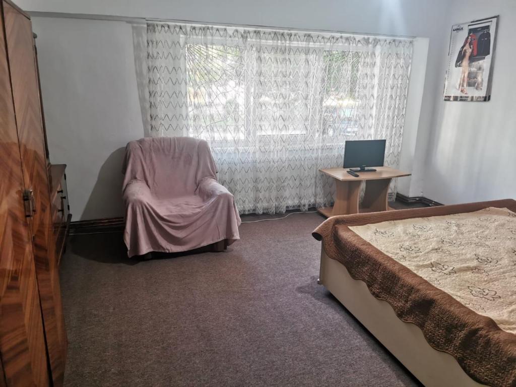 - une chambre avec un lit, une chaise et un bureau dans l'établissement Garsonieră, à Craiova