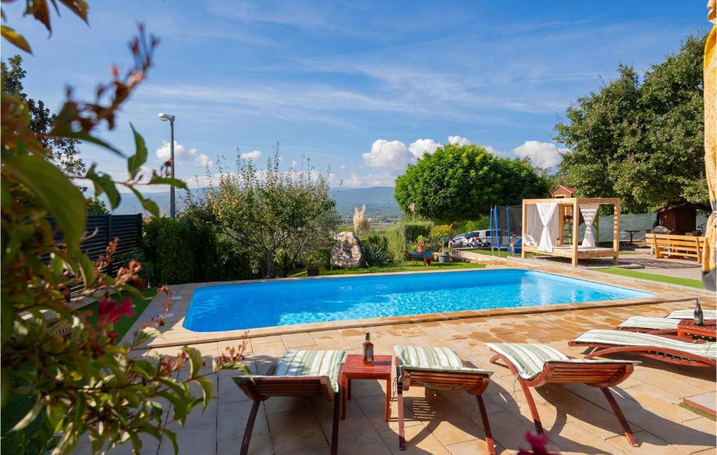 a swimming pool in a yard with chairs and a table at Stunning Home In Vinjani Donji With 5 Bedrooms, Wifi And Outdoor Swimming Pool in Majići