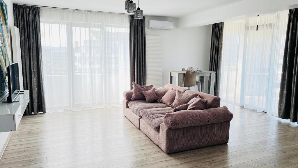a large couch in a living room with windows at Apartament Dem Rădulescu Lidl in Râmnicu Vâlcea