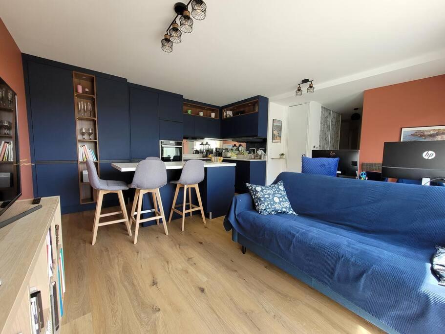 un salon avec un canapé bleu et une cuisine dans l'établissement F3 neuf tout équipé de 62m2 centre ville, à Annecy