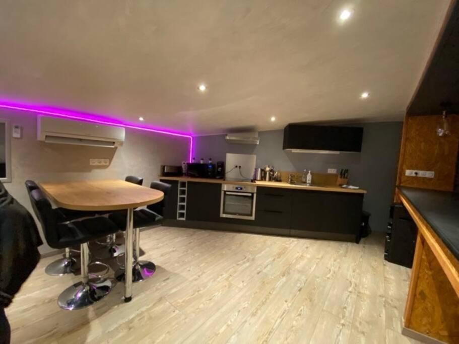 a kitchen with a table and purple lights in a room at Au pool house de la Faye avec jacuzzi in Saint-Romain-Lachalm