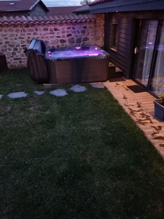 a backyard with a hot tub in the yard at night at Au pool house de la Faye avec jacuzzi in Saint-Romain-Lachalm