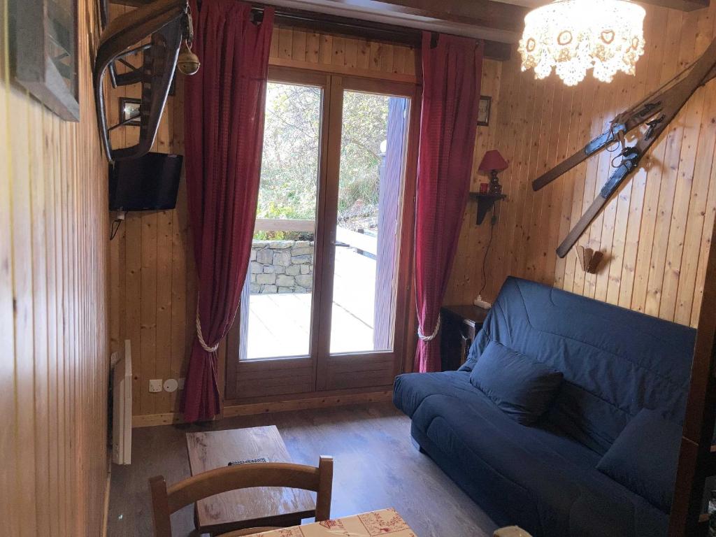 un salon avec un canapé bleu et une fenêtre dans l'établissement Appartement cosy 3 pers, proche pistes et navette, parking privé - FR-1-467-116, au Grand-Bornand