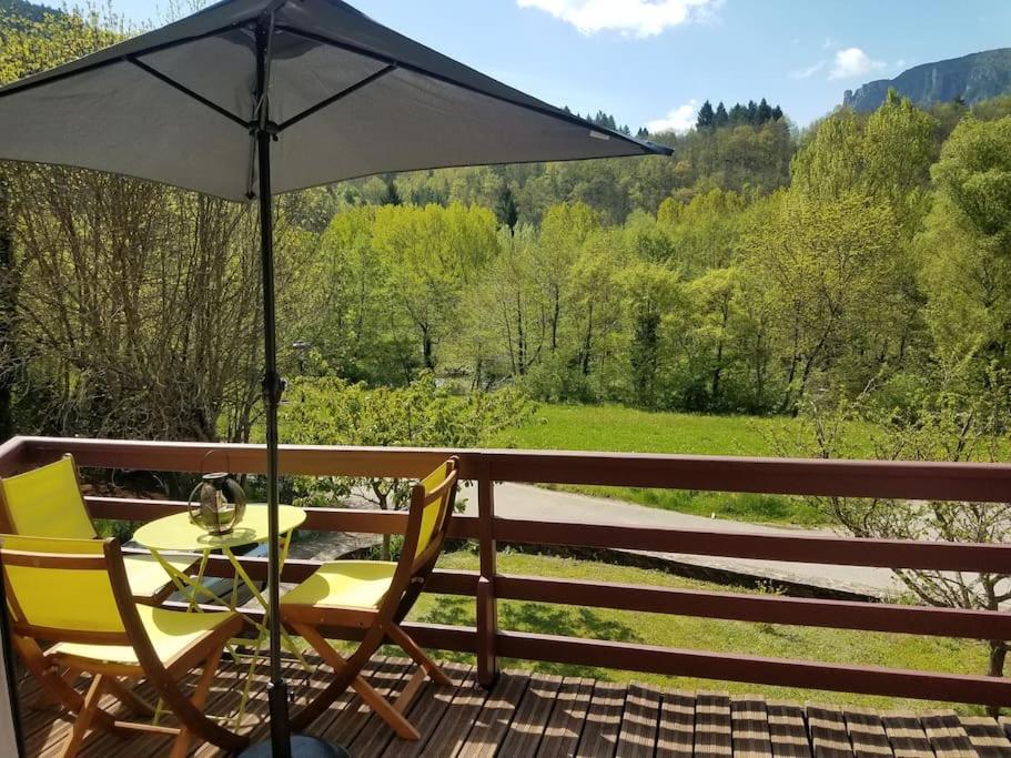 une table et des chaises sur une terrasse avec un parasol dans l'établissement Chambres et coin repas Coco Eco, à Bédouès
