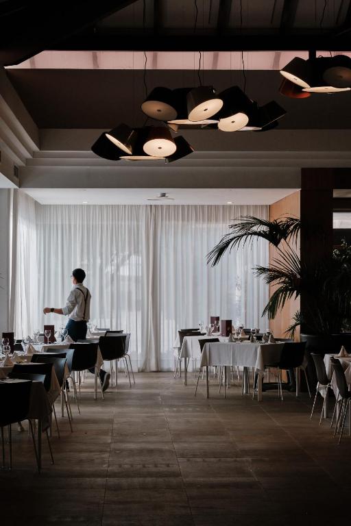 a man standing in a dining room with tables and chairs at Prinsotel La Dorada & Spa in Playa de Muro