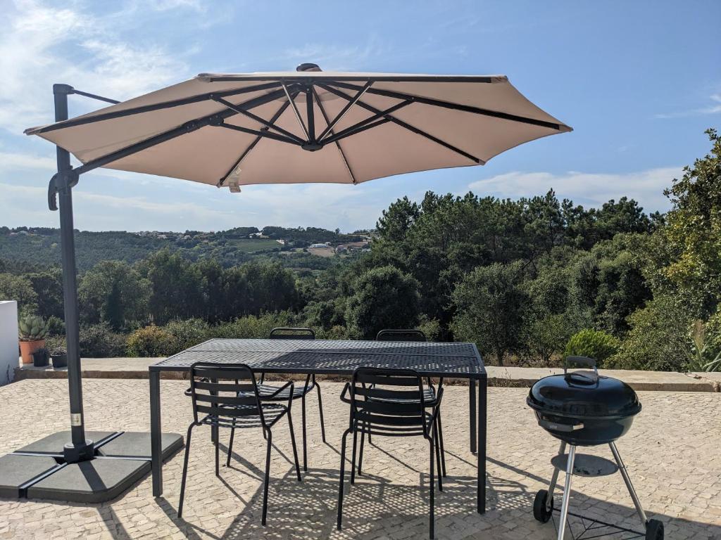 une table et des chaises avec un grill et un parasol dans l'établissement Modern and spacious Cork House with private valley view, à Caldas da Rainha