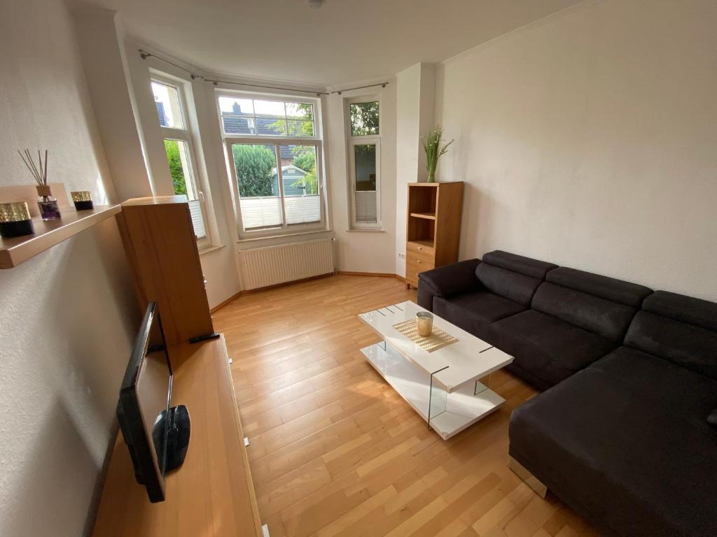 Apartment in guter Lage für bis zu 5 Personen في أولدنبورغ: غرفة معيشة مع أريكة سوداء وطاولة
