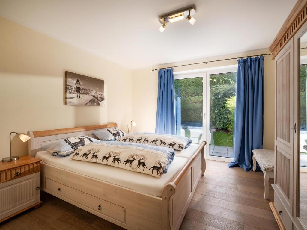 a bedroom with a bed with blue curtains and a window at Alpensuiten in Ellmau