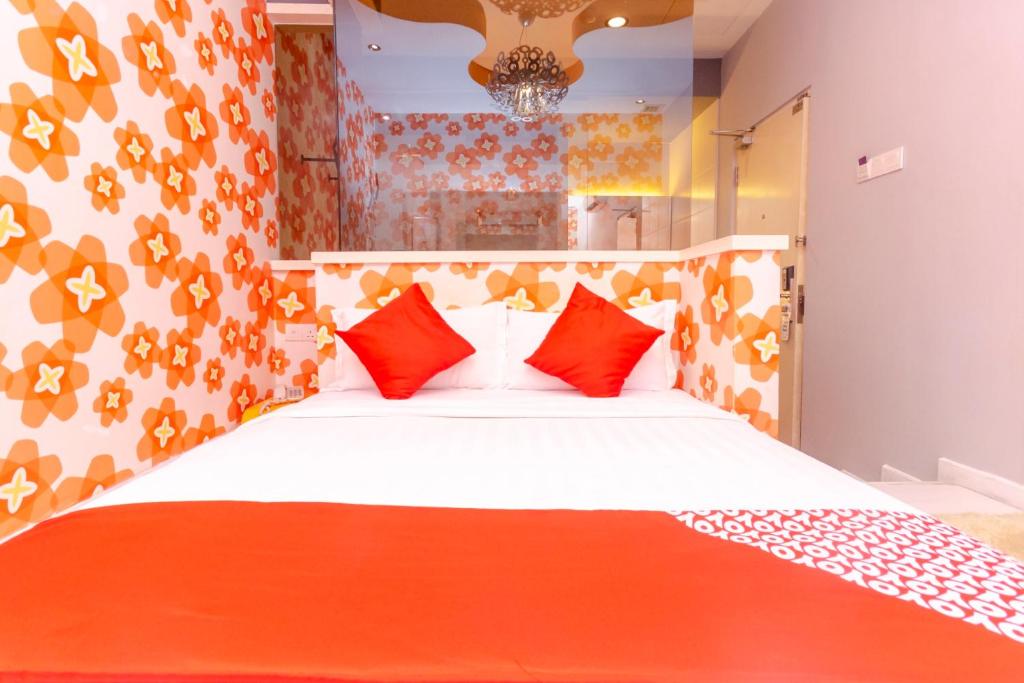 1 dormitorio con 1 cama blanca grande con almohadas rojas en OYO 902 Rooms Boutique Hotel, en Johor Bahru