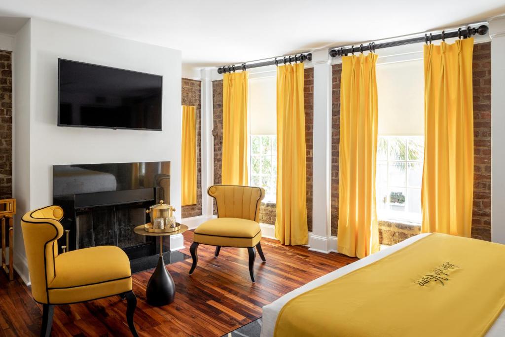 a bedroom with a bed and a chair and a fireplace at The Vendue, Downtown Art Hotel in Charleston