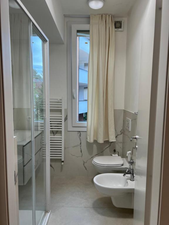 baño con 2 aseos, lavamanos y ventana en Casa San Michele, en Sassuolo
