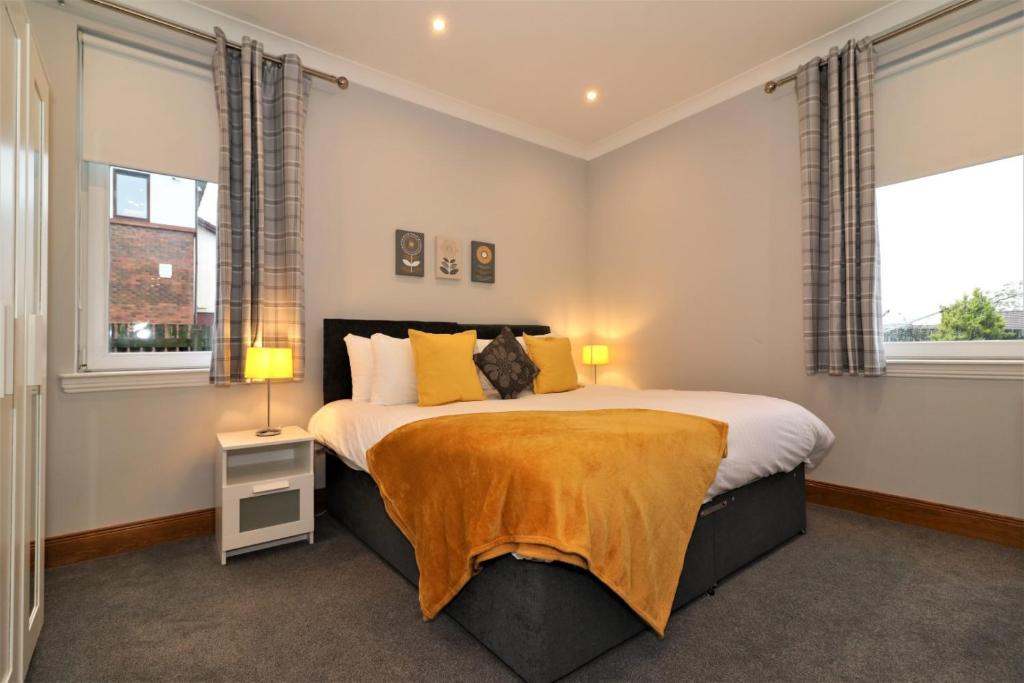 a bedroom with a large bed with two windows at Greenlees Clubhouse 3 Bed in Cambuslang