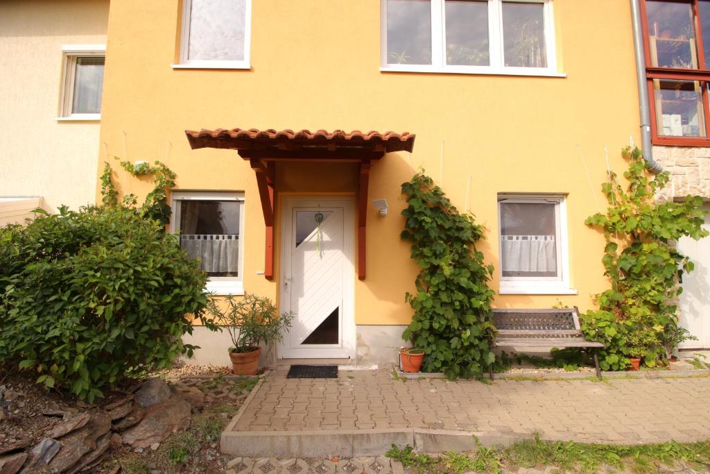 a yellow house with a white door and a bench at Kleine Wohngelegenheit am Stadtrand von Chemnitz in Chemnitz