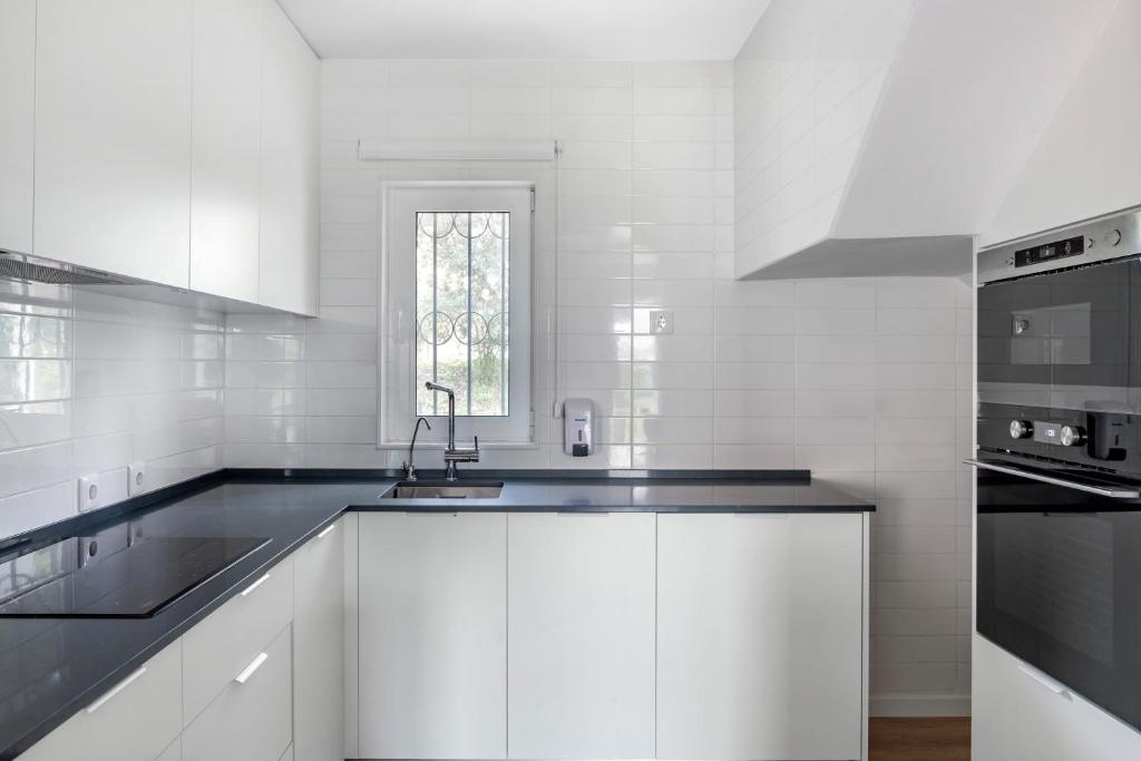 a white kitchen with white cabinets and a sink at Vilar do Golf in Quinta do Lago