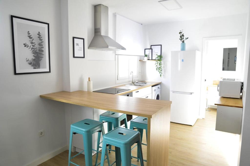 a kitchen with a wooden counter and blue stools at El Apartamento de Nueva in Cádiz