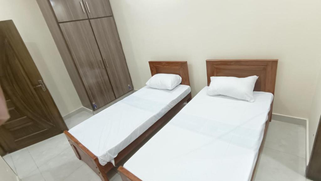 two twin beds in a room with a closet at Continental Boys Hostel R-2 Johar Town in Lahore