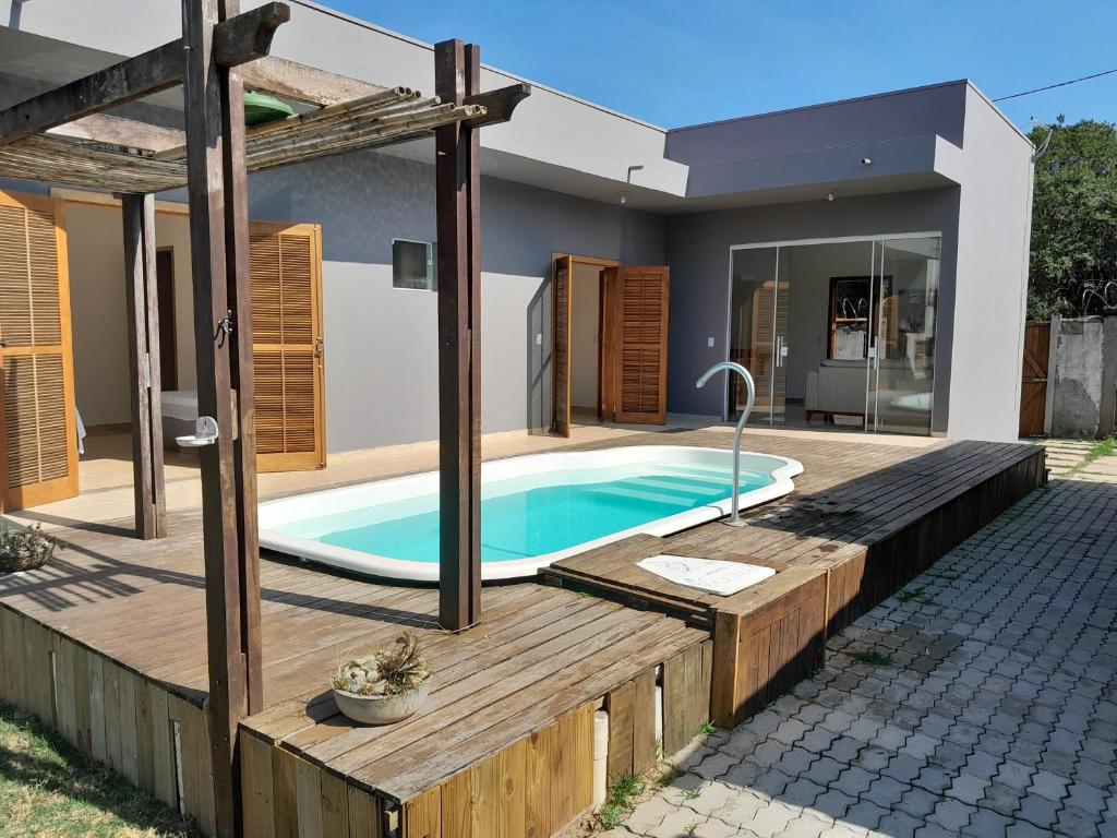 a swimming pool with a wooden deck and a house at Rancho Calamaris in Cananéia