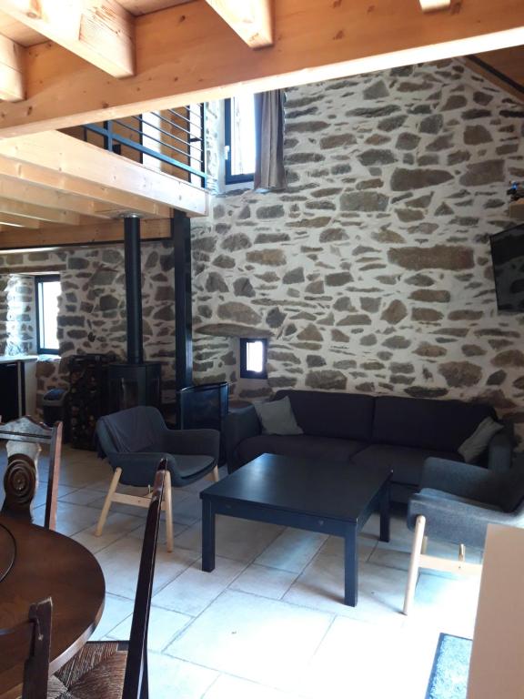 a living room with a couch and a stone wall at CHALET AULIAN in Grust