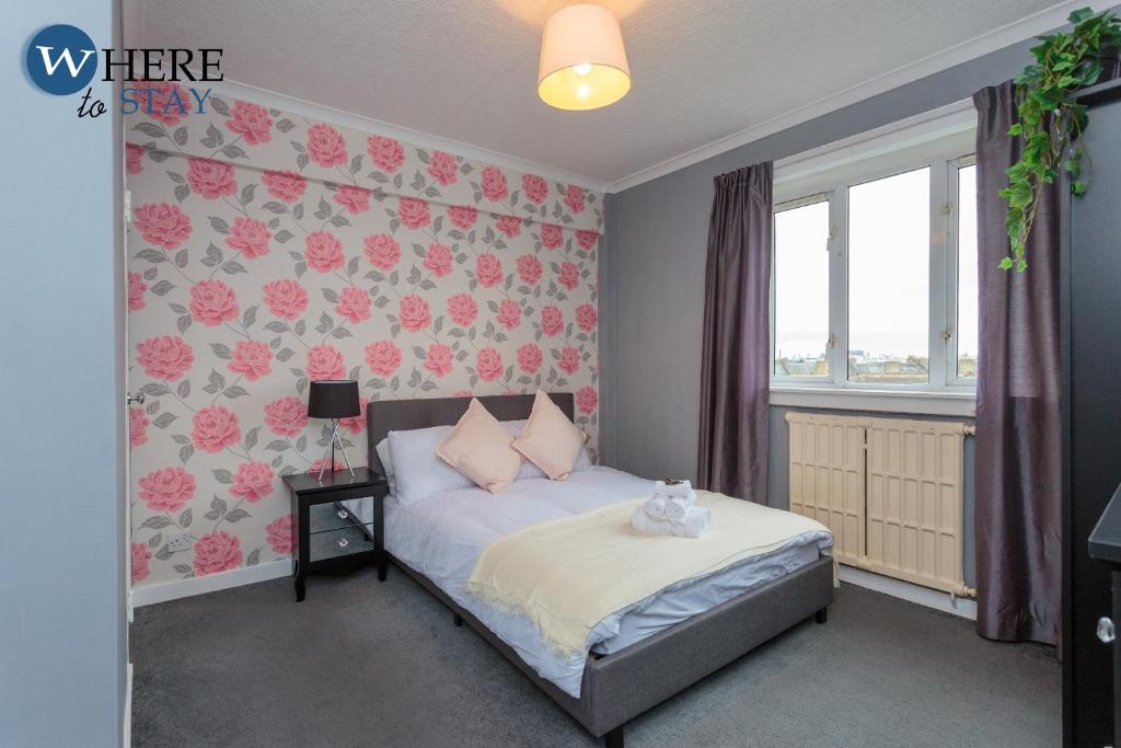 um quarto com uma cama com papel de parede floral cor-de-rosa em Stunning 3 bedroom apartment Edinburgh em Edimburgo