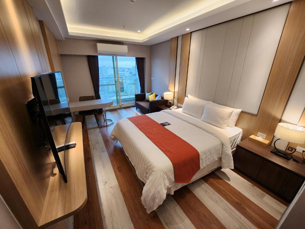 een slaapkamer met een bed, een bureau en een televisie bij Bentley Hotel in Zhongli