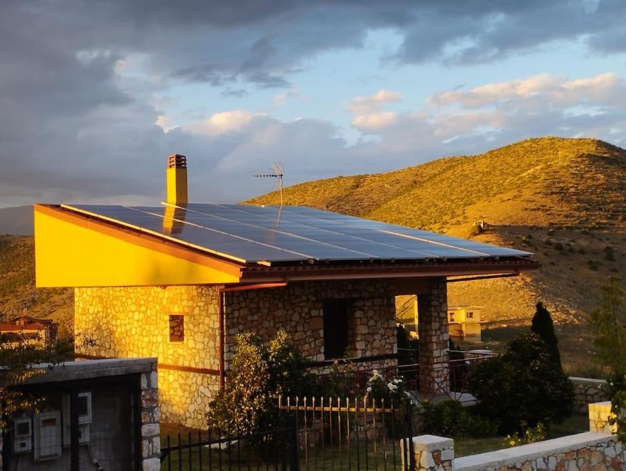 a house with a solar roof with a mountain in the background at ΒΙΟΚΛΙΜΑΤΙΚΟ ΗΛΙΟΠΕΤΡΟΣΠΙΤΟ στην ΑΡΧΑΙΑ ΒΟΚΕΡΙΑ in Peraía