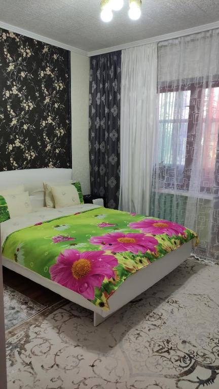 a bedroom with a large bed with a flower blanket at Restful sleep apartments in Karakol