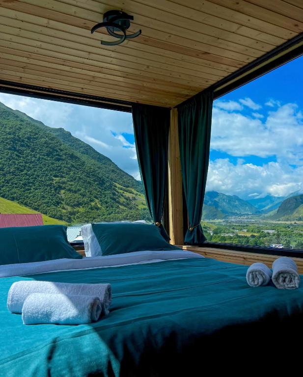 a bed in a room with a large window at Kazbegi Inn Cottages in Kazbegi